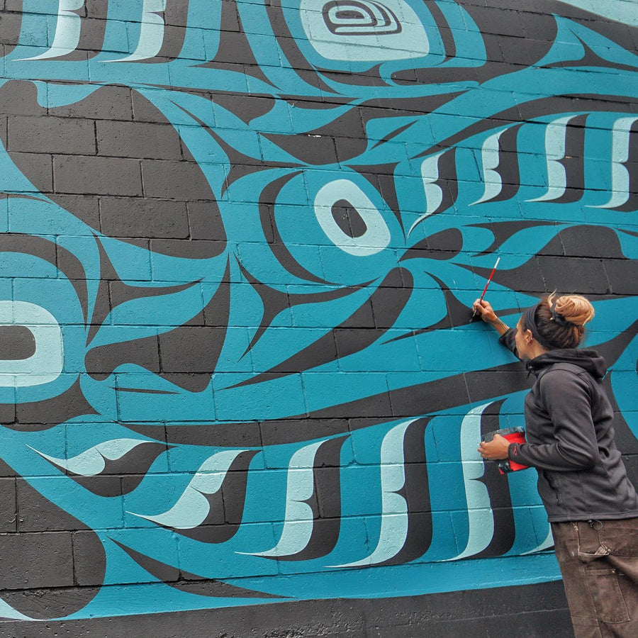 Artist Kari Morgan from the Outdoor Artist Collective Painting an indigenous mural on the wall 
