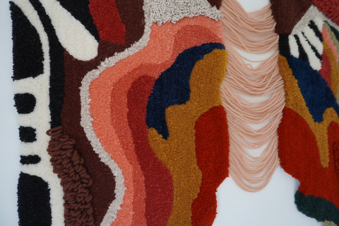 A close up look to "Riverside" by Josiane Saboia. Riverside is a wall rug embroidered with 100% wool and cotton. The idea of ​​​​this rug is to show in an abstract way, depicting the banks of rivers.